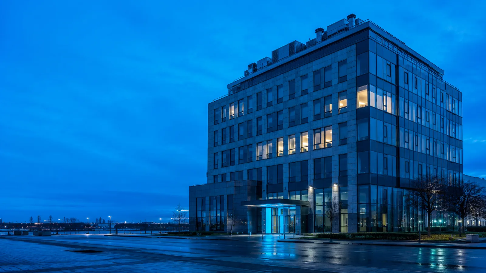 A multi-storey commercial building lit from within at dusk